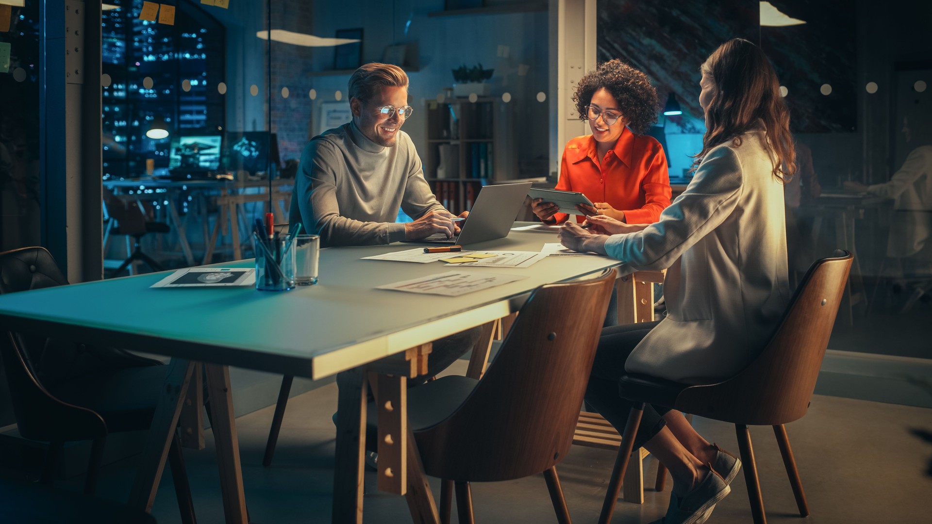 Positive Group of Managers Having a Team Meeting Long After Work Hours in the Night. Inspired Colleagues Discussing Annual Financial and Marketing Reports. Teamwork in Creative Office.